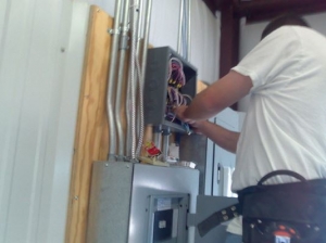 A professional electrician services an electric panel during a project near Detroit, MI.